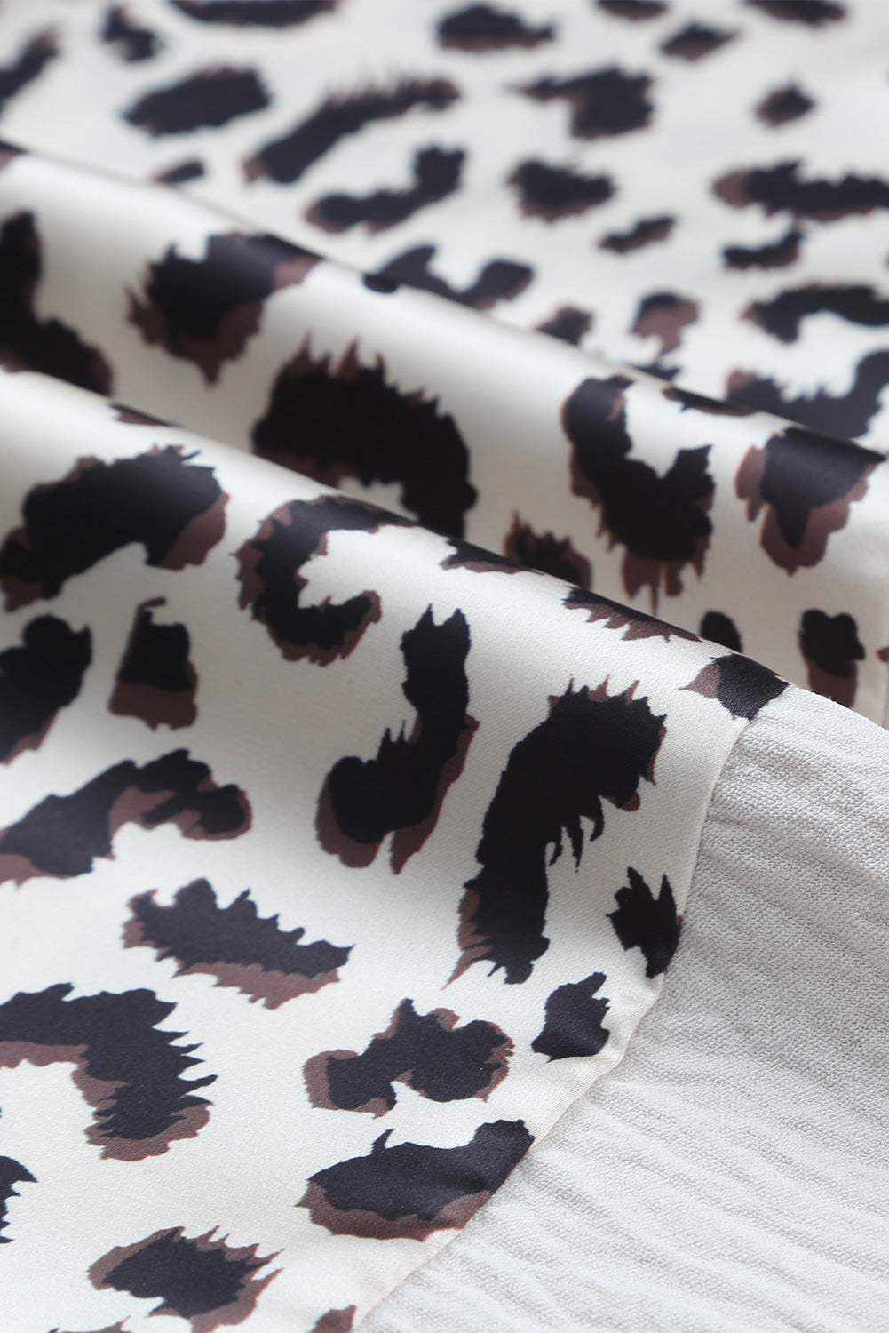 close-up of leopard color block fabric with black and brown spots on white background for blouse